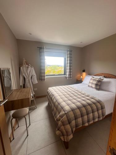 a bedroom with a bed and a desk and a window at Sputieburn Bothy in Brora