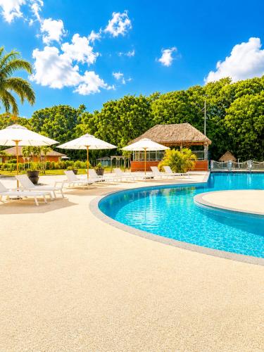 a resort swimming pool with umbrellas and chairs at Le Cocon Miel - Plage, Jardin, Adapté aux Groupes in Folle Anse