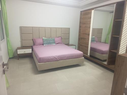 a bedroom with two beds and a mirror at Studio en rez-de-chaussée in Hammamet