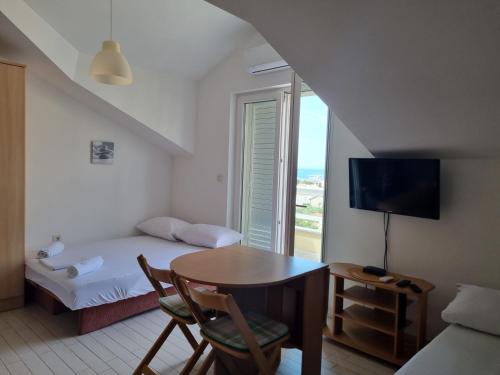 ein Zimmer mit einem Bett, einem Tisch und einem Fernseher in der Unterkunft View - Novalja in Novalja
