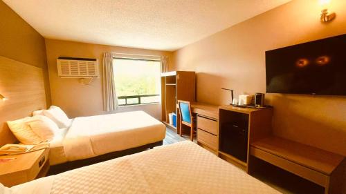 a hotel room with two beds and a flat screen tv at Econo Lodge Airport Quebec in Quebec City