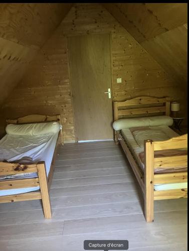 a room with two beds in a wooden cabin at La petite maison sur la colline in Rue