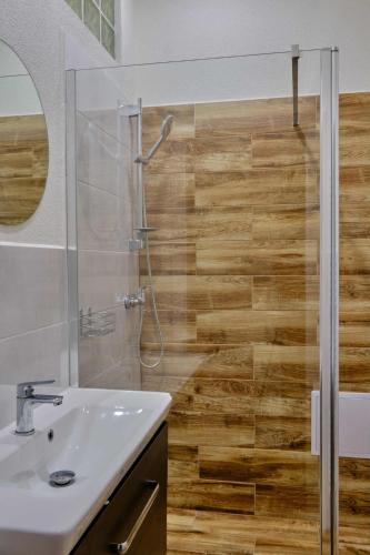 a bathroom with a sink and a shower with wooden floors at Villa Axa in Vrbov