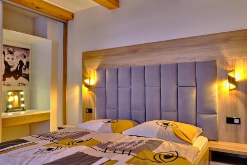a bedroom with a bed with a purple headboard at Villa Axa in Vrbov