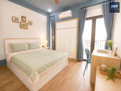 a bedroom with a bed and a desk and a window at JOY APARTMENT TAY HO in Hanoi