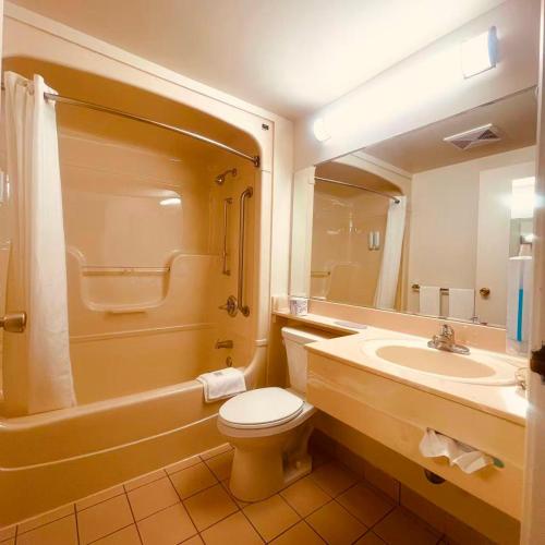 a bathroom with a toilet and a sink and a mirror at Econo Lodge Airport Quebec in Quebec City