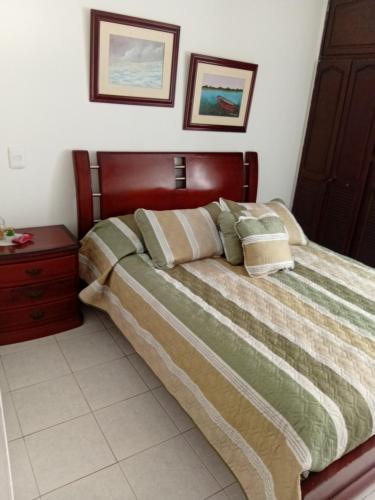 a bedroom with a bed with a wooden headboard at Habitación Conj parque San Agustín, Floridablanca in Floridablanca
