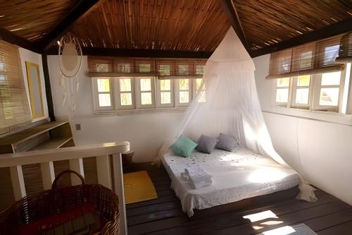 a bedroom with a bed in a room with windows at Casa Capela - Para quem ama ficar na beira do mar in Marau