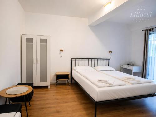 ein Schlafzimmer mit einem großen weißen Bett und einem Tisch in der Unterkunft Hotel Liliacul in Cluj-Napoca