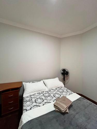 a bedroom with a bed and a dresser with a book on it at Casa Completa à 100m do Parque de Exposição in Patos de Minas