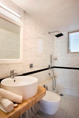 a white bathroom with a sink and a toilet at Avion Holiday Resort in Lonavala