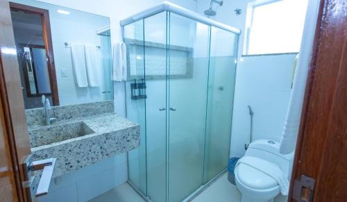 a bathroom with a glass shower and a toilet at Vitoria Regia Praia Hotel in Porto Seguro