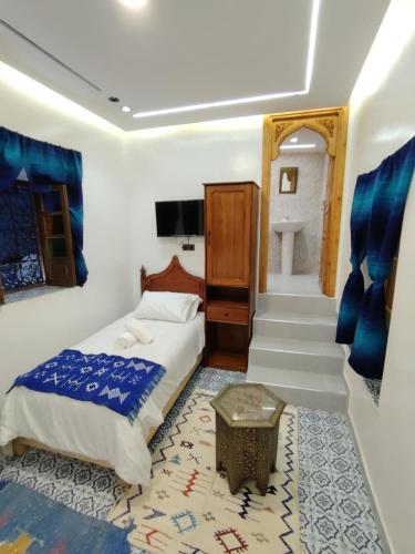 a bedroom with a bed and a table and stairs at FATI GUEST HOUSe in Chefchaouen