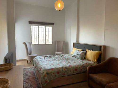 a bedroom with a bed and a chair and a window at Beit Rifi Mountain Escape, with intex pool, Feitroun in Al ‘Aqabah