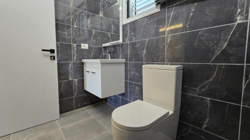 a bathroom with a toilet and a black tiled wall at Vila Qetesia in Përmet