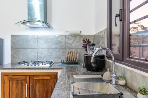a kitchen with a sink and a stove at Le havre des palmiers in Tsivonoabe