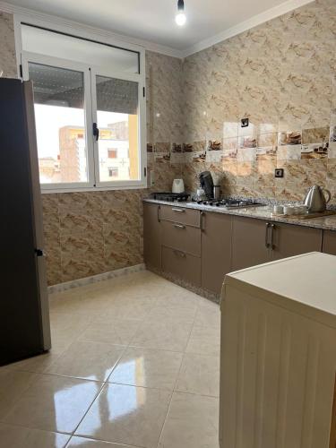 a kitchen with a refrigerator and a counter in it at Atouli Suites in Nador