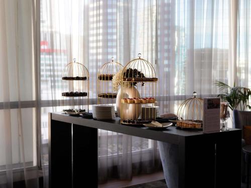 a table with several bird cages filled with pastries at Mövenpick Hotel Auckland in Auckland