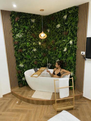 Eine Frau sitzt in einer Badewanne vor einer grünen Wand in der Unterkunft Maison Frattasio in Neapel