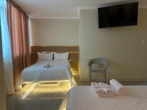 a bedroom with two beds and a tv on the wall at Hotel Danmar in Ventanas