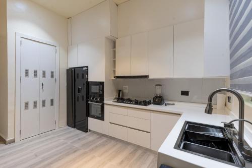 a kitchen with white cabinets and a black refrigerator at Luxe Haven in Lekki