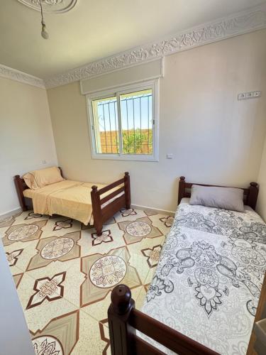 a bedroom with two beds and a tiled floor at Ahmed sarii in Asilah