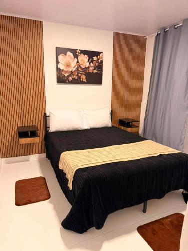 a bedroom with a large bed with a black blanket at Recanto dos pássaros in Guapimirim