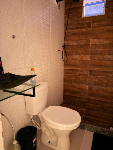 a bathroom with a toilet and a glass shelf at Recanto dos pássaros in Guapimirim