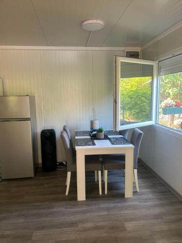 a dining room with a table and chairs and a refrigerator at Villa Viva Jama in Novi Sad