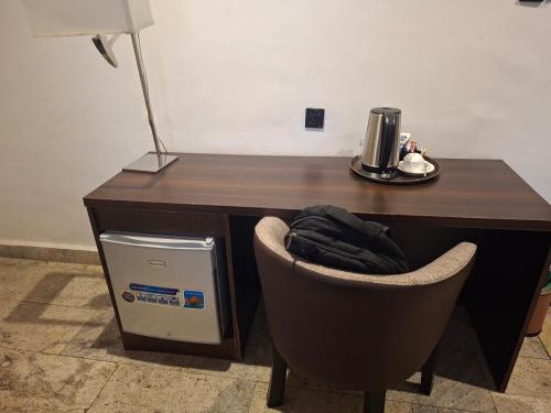 a desk with a chair in front of a desk with a coffee maker at Danville Hotel Ltd in Freetown