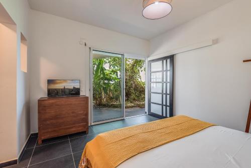 a bedroom with a bed and a large window at T3 Moderne avec piscine Oasis de nature et Sérénité in Petit-Canal
