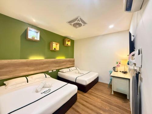 a room with two beds and a desk in it at Smile Hotel Danau Kota in Kuala Lumpur