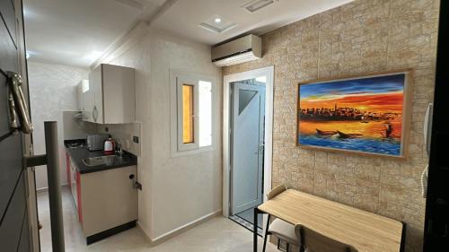 a kitchen with a table and a painting on the wall at Appartement Agadir Tilila 1 pour couples mariés et familles in Agadir