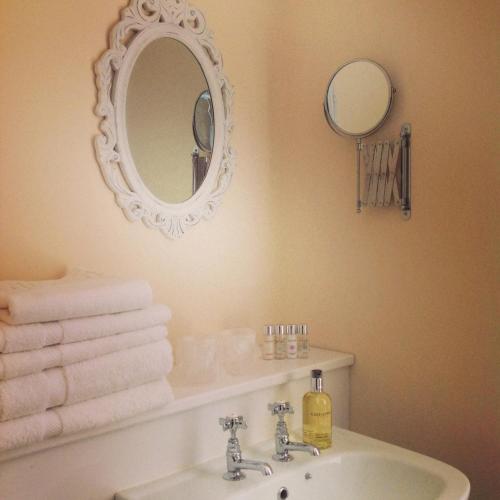 a bathroom with a sink and a mirror and towels at Fring House Bed and Breakfast in Seaton