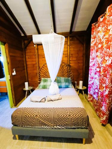 a bedroom with a bed with a net at Gites kaz à klemence - Bungalow karapat - jacuzzi privé et piscine partagée au cœur de la nature à Anse-Bertrand in Anse-Bertrand