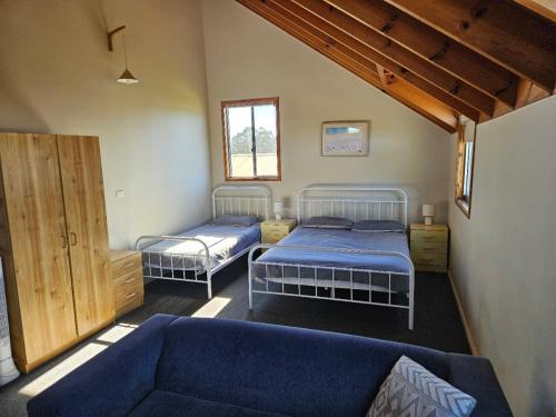 a bedroom with two beds and a couch in it at Billungar Unit 1 at Hat Head - 1 Creek Street in Hat Head