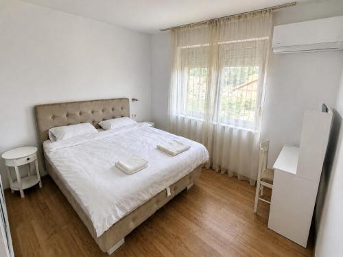 a white bedroom with a large bed and a window at Tara Holiday Home in Mojkovac