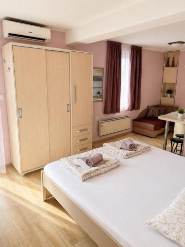 a bedroom with a large bed with two towels on it at Apartmani Erdeljanov in Soko Banja