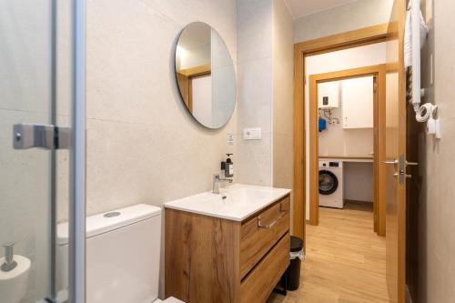 a bathroom with a sink and a toilet and a mirror at Apartamentos Liérganes Centro II in Liérganes