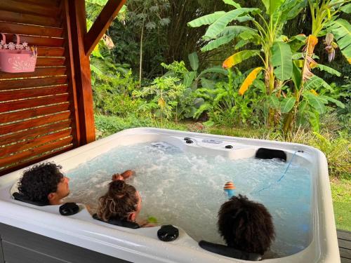 two people in a jacuzzi tub in a garden at Maison cosy à Lamentin, 20m², climatisation in Lamentin