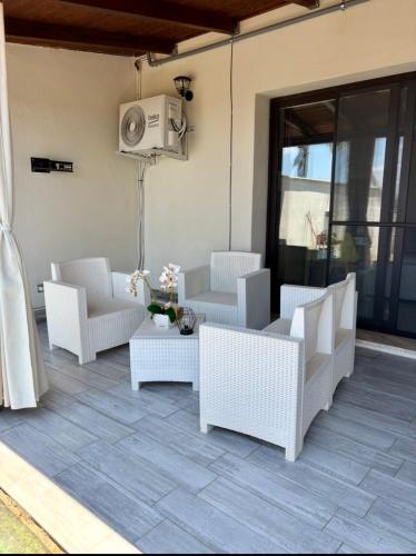 eine Terrasse mit weißen Korbstühlen und einem Tisch in der Unterkunft Villa ManuCamp in Reggio di Calabria