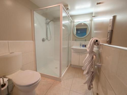 a bathroom with a shower and a toilet and a sink at Athena Motel in Christchurch