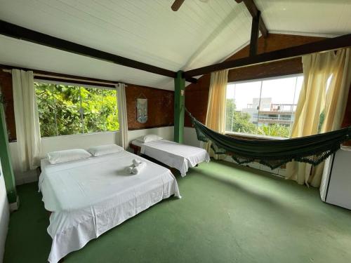 a room with two beds and a hammock in it at Pousada e Chocolateria Muito Mais in Itaparica
