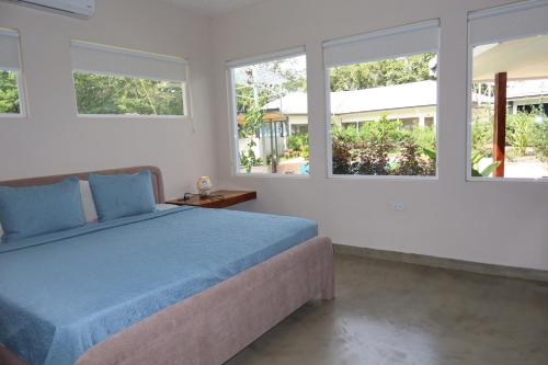 a bedroom with a blue bed and three windows at Casa Frank - Sophiassuites506 in Brasilito