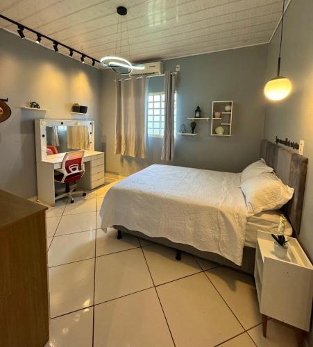 a bedroom with a bed and a desk and a chair at Casa Larissa in Presidente Figueiredo