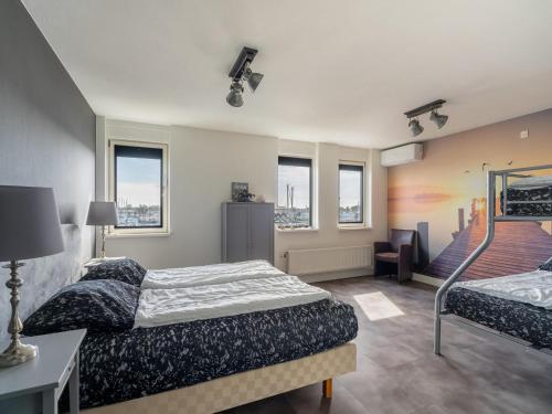 a bedroom with two beds and a chair and windows at De Brouwersdam in Ouddorp