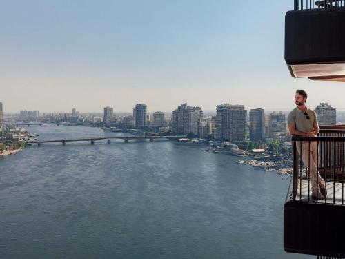 a man standing on the edge of a balcony overlooking a river at Sofitel Cairo Nile El Gezirah in Cairo
