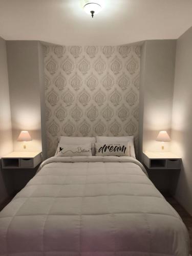 a bedroom with a large white bed with two lamps at Dpto Plaza Colon in Azul
