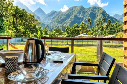 a table on a balcony with a view of mountains at Teahupo'o Lodge Tahiti - Maison familiale au cœur du village - Canoës inclus in Teahupoo