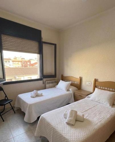 a hotel room with two beds and a window at Los Hermanos in Viladecáns
